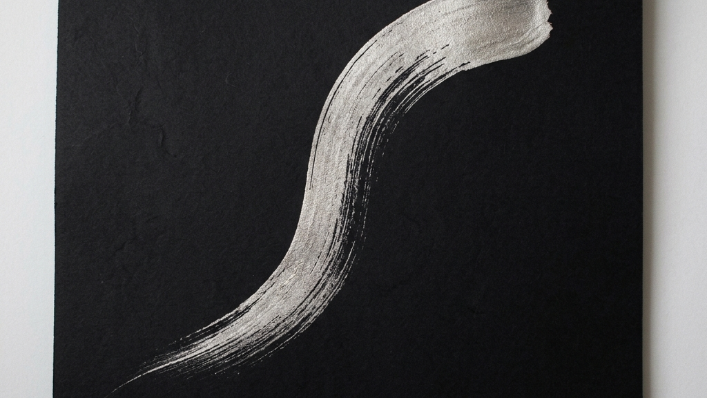 完全なる漆黒のキャンバスに、プラチナ色をした金属のしずくが一本の鳥の尾羽のような美しい曲線を描いた抽象芸術