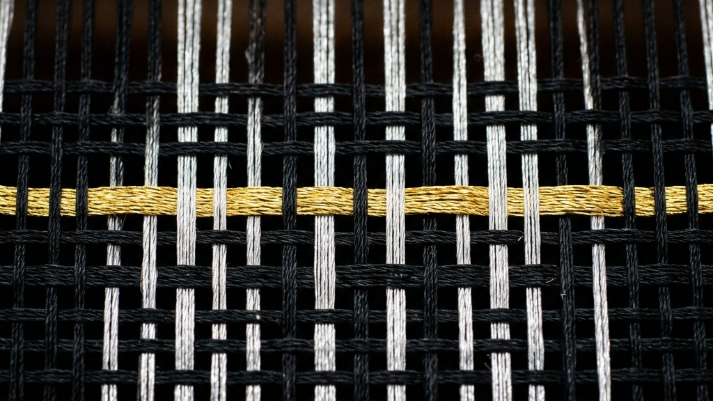 銀色と黒の糸が直線的に交差する、機織りのグリッド構造を限界まで接写したマクロ撮影