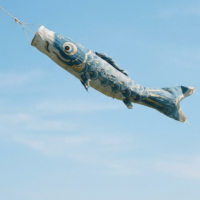 静かな青空を背景にミニマルに描かれる手描きこいのぼりと加須市の手仕事の概念図